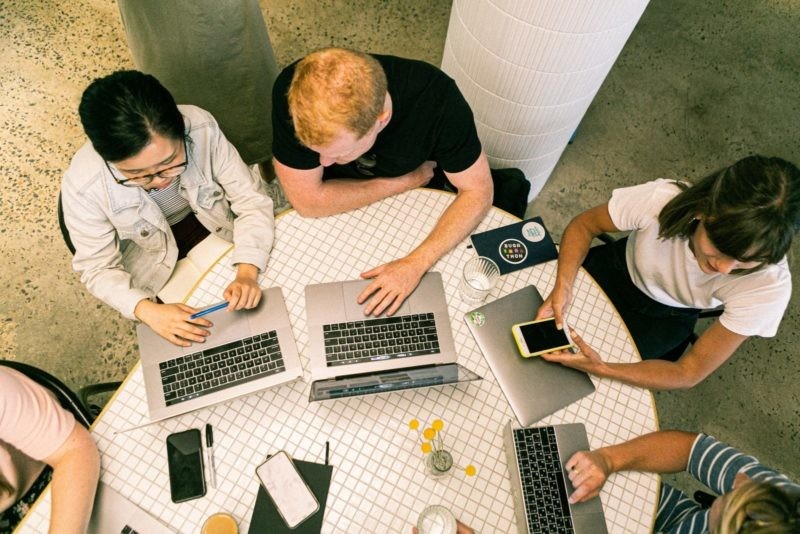 Birdseye view of people at a table using laptops and phones