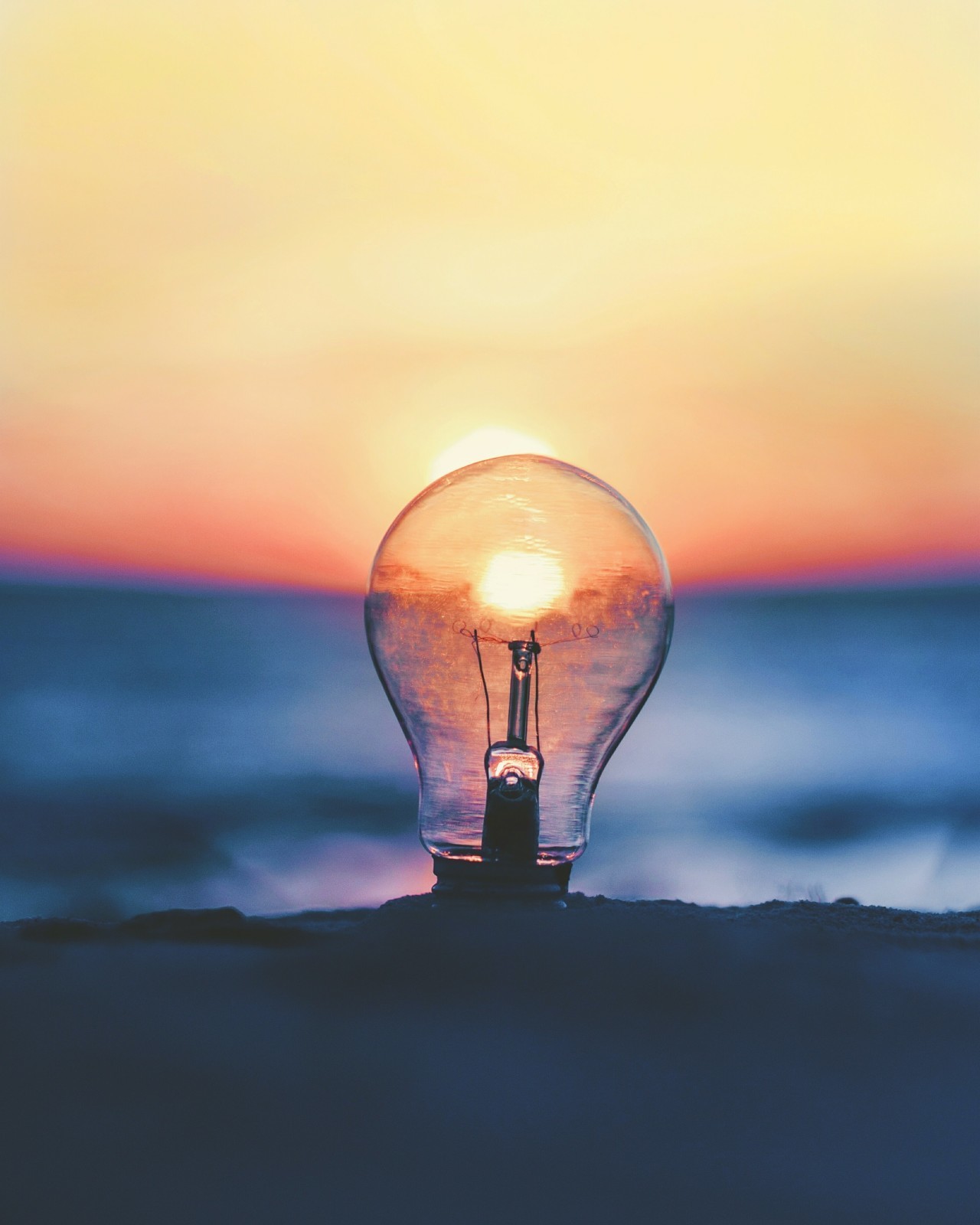 Lightbulb in front of a sunset - Photo by Ameen Fahmy